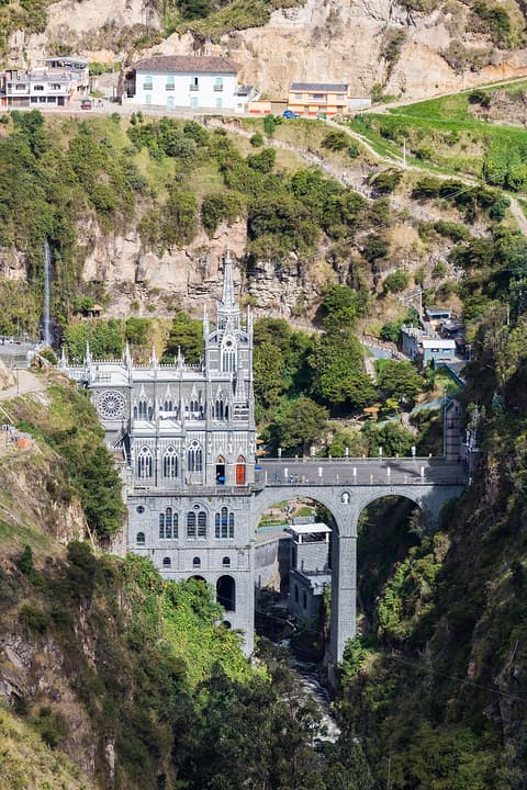 El santuario y su puente vistos desde el otro lado del cañón, con una cascada y casas en lo alto.